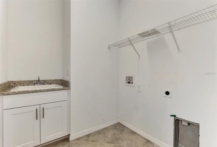 laundry room with built in cabinets and a sink