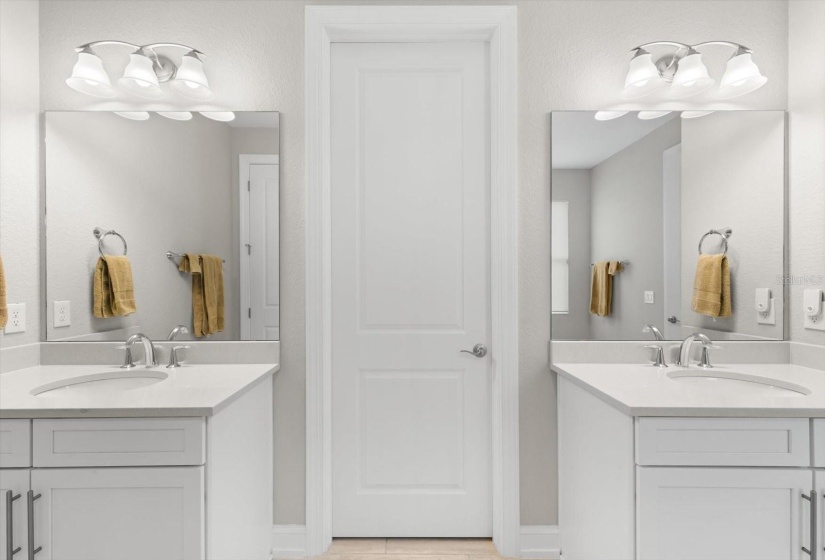 Walk in closet in-between the split vanities with quartz counter tops & chrome fixtures.