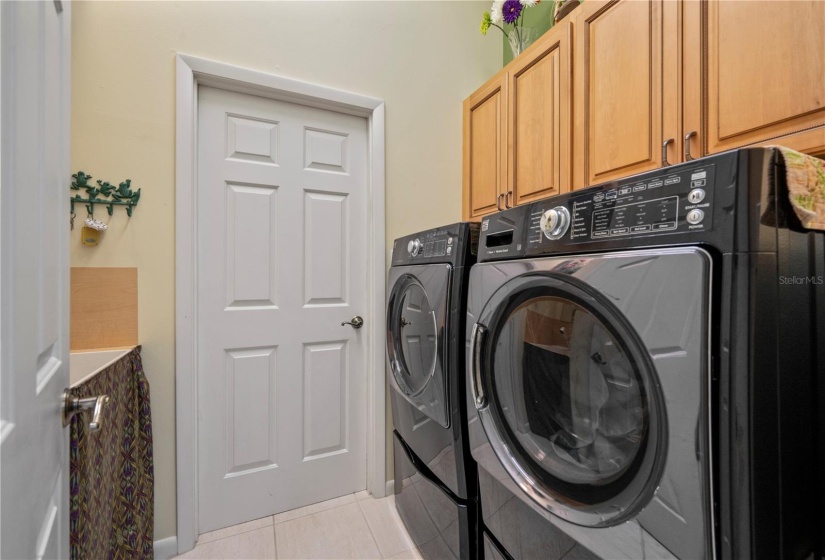 Laundry between kitchen/garage includes storage closet, cabinets and utility sink