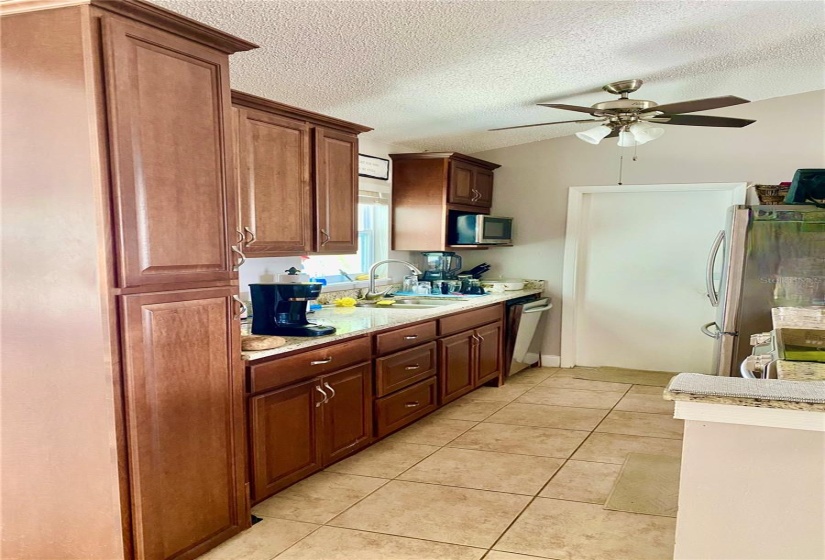 Galley Kitchen with Granite Counters, Double Stainless Sink, Ceiling Fan....Door Leads Into the Garage & Laundry Area