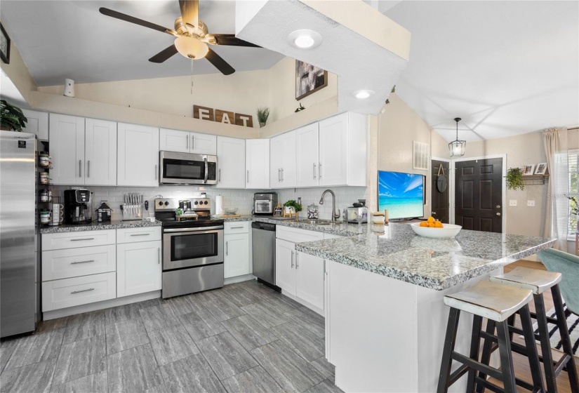 KITCHEN WITH GRANITE COUNTERTOPS, STAINLES STEEL APPLIANCES, TILE FLOOR AND PLANT SHELVES