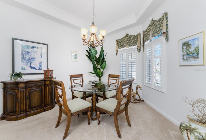 Light and bright formal dining area features a tray ceiling and pretty chandelier.