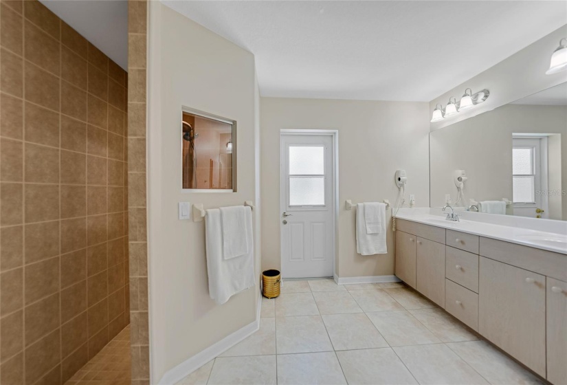 Primary ensuite with access door to lanai & pool area, large walk in shower and dual sinks pictured here