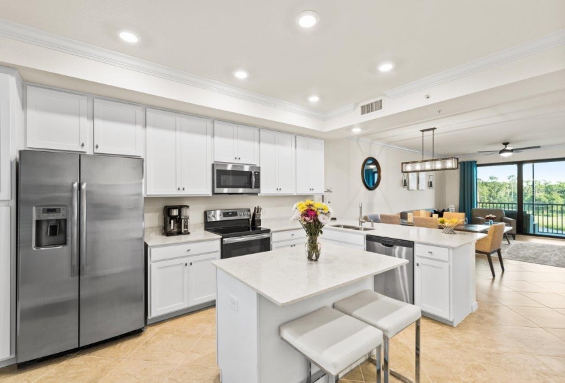 Gourmet kitchen featuring quartz countertops, stainless steel appliances, wood shaker cabinets, a breakfast bar, and island.