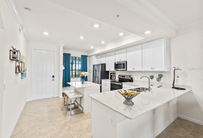 Gourmet kitchen featuring quartz countertops, stainless steel appliances, wood shaker cabinets, a breakfast bar, and island.