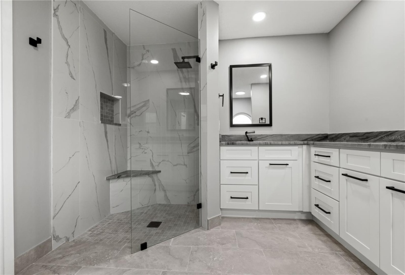 Luxurious walk-in shower with seat, dual sinks, solid stone counters and designer type faucets