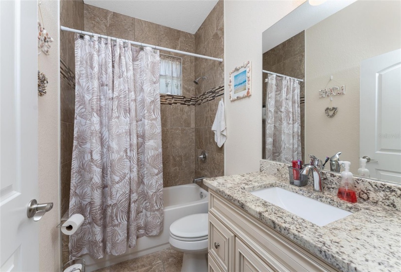 Guest bathroom with wood vanity, level 5 granite and tiled walk-in shower