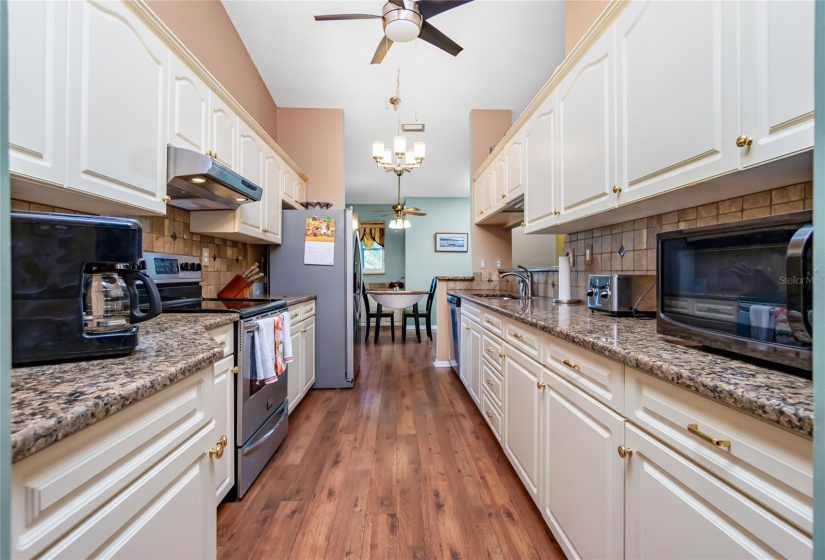 Kitchen with hardwood floors, wood cabinetry and granite counters.