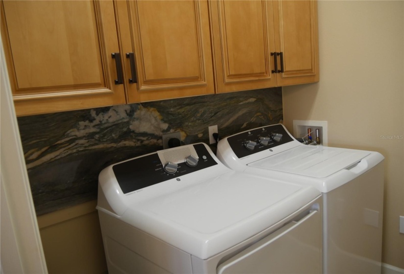 The attention to detail on this renovation includes more of this exotic granite in the laundry room with custom  cabinets with crown molding and a granite slab backsplash on the left side!!!