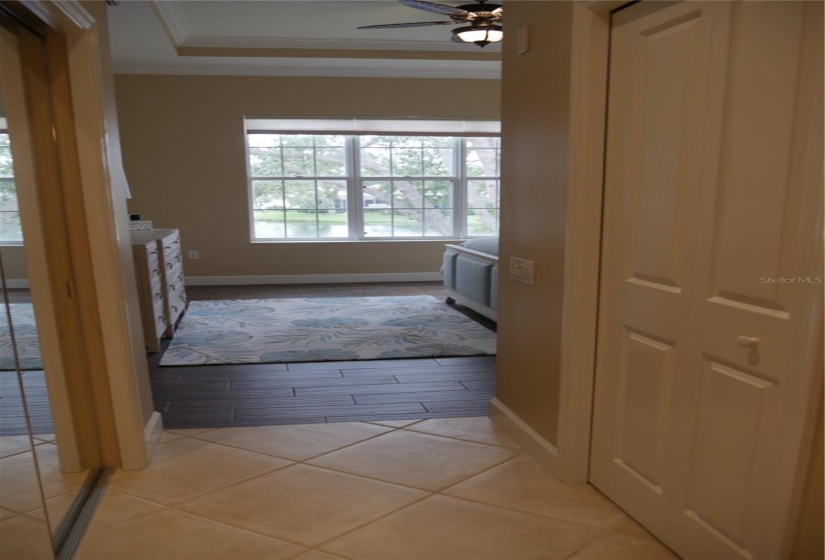 The view from the linen closet into the primary bedroom with a lineal closet on the left and a substantially large walk-in closet on the right.