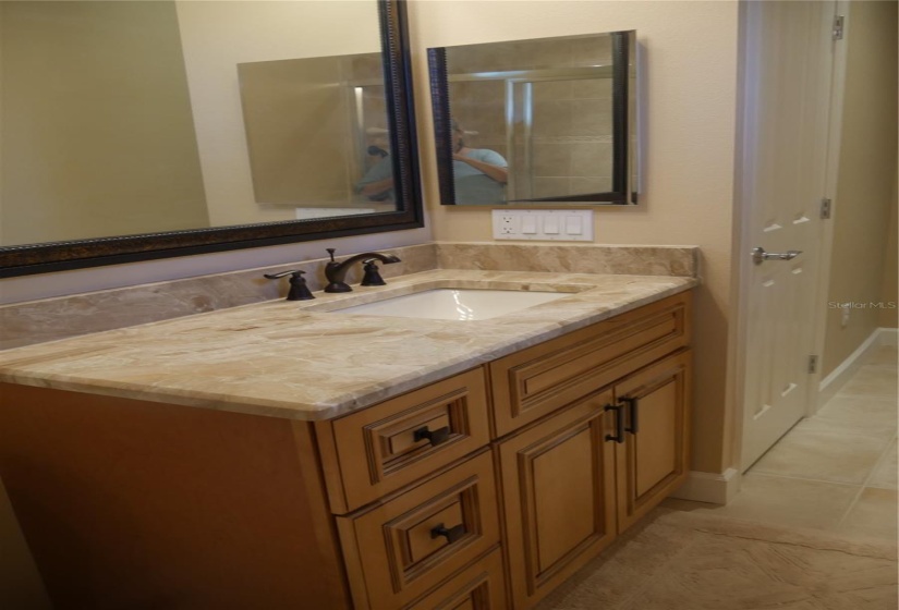 The second full bath / ensuite has also been renovated with custom cabinetry, mirror, all new fixtures, lighting and more of the gorgeous marble like the Primary bath! The linen closet is to the right of the vanity and the shower is to the left.