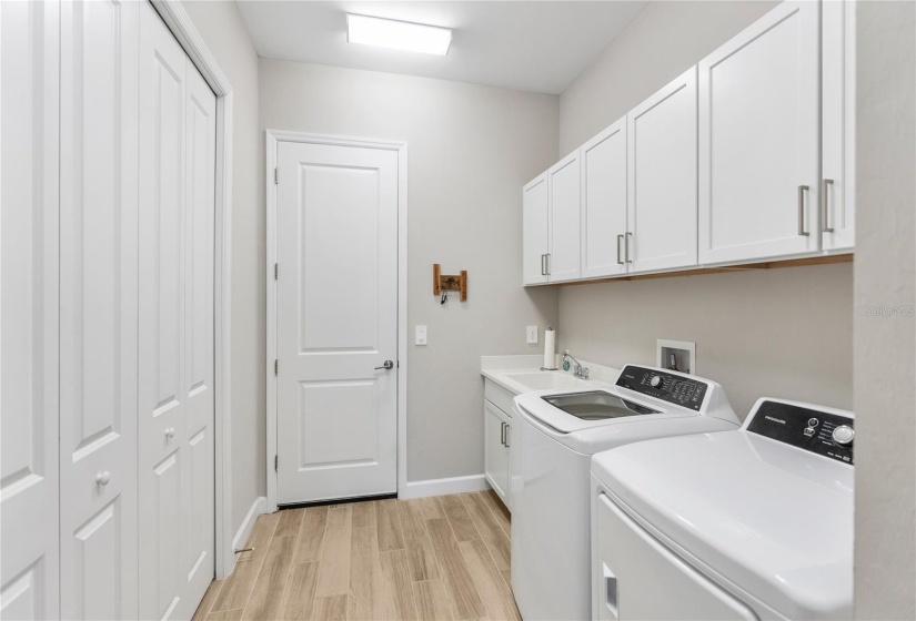 Laundry Room with ample cabinetry, storage closet and utility sink