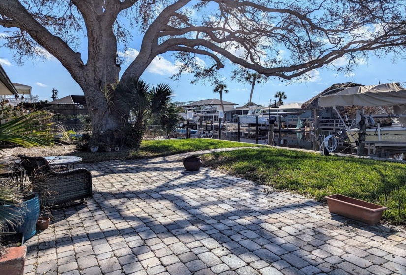 Paver patio in rear of home with one large oak tree on the property.